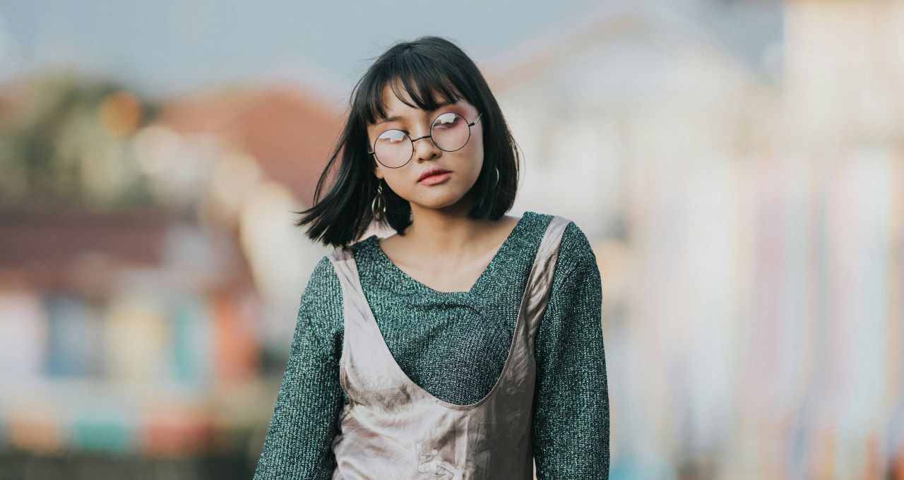 Femme avec des lunettes rondes et un carré frangé en train de marcher dans la rue