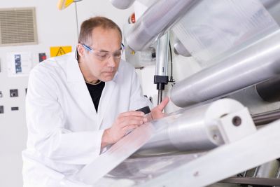 technician checking production of flexible laminate on machine