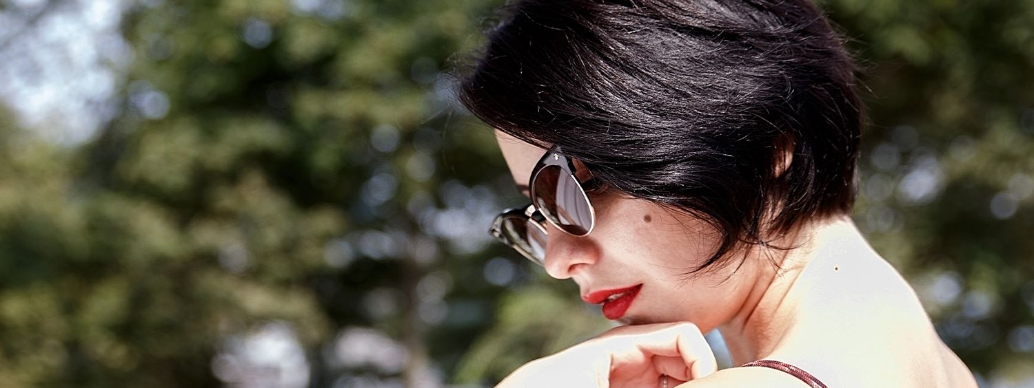 Profil de femme avec de beaux cheveux bruns lumineux et des lunettes de soleil