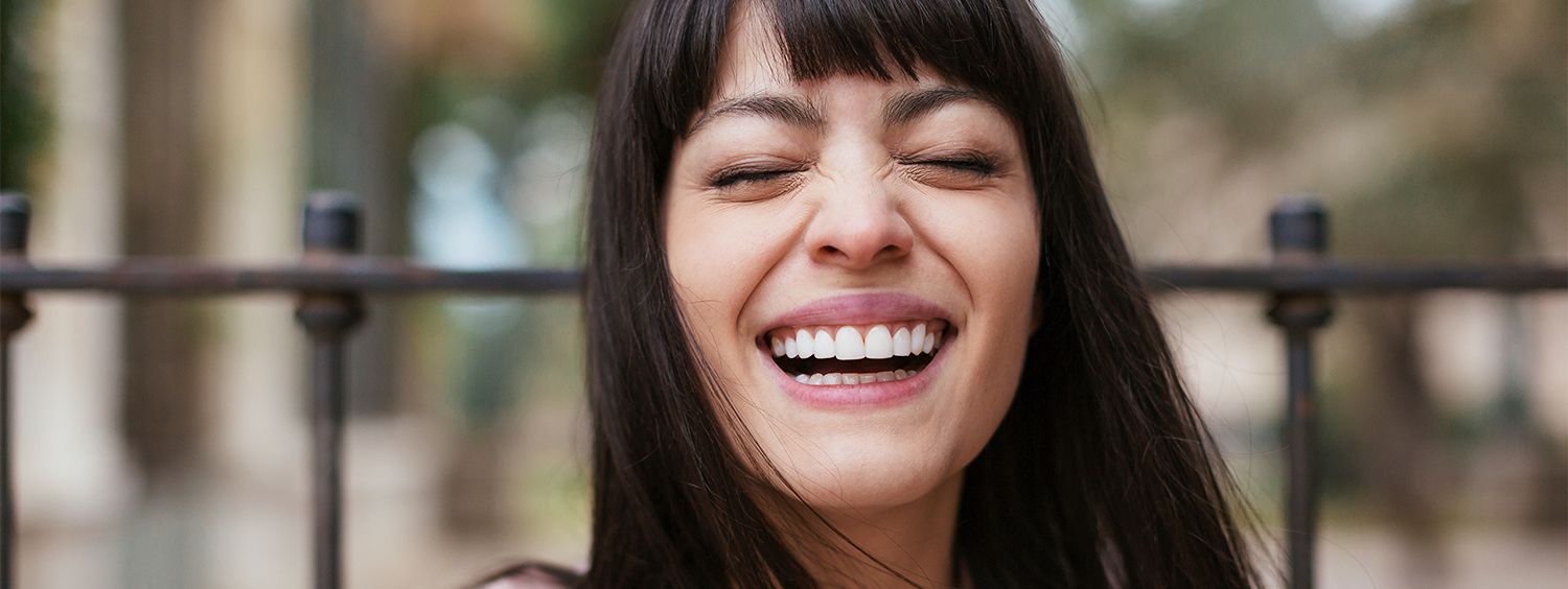 Femme brune avec une frange droite en train de rire