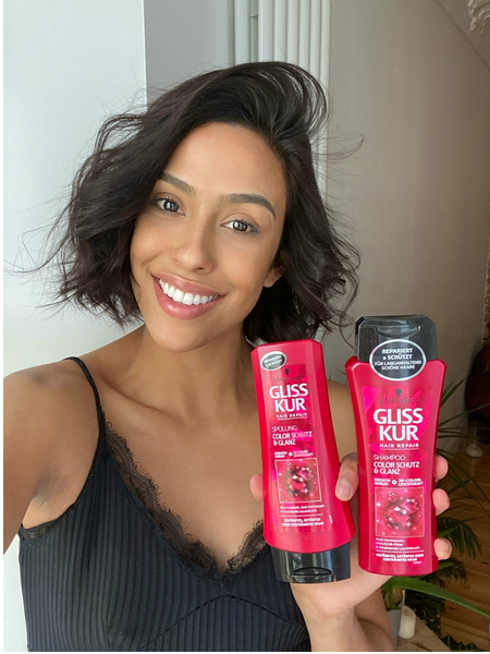 Woman with healthy curls holding Gliss Color Protect products