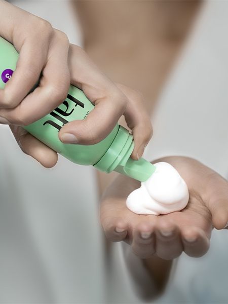 Woman dispensing Taft mousse into the palm of her hand