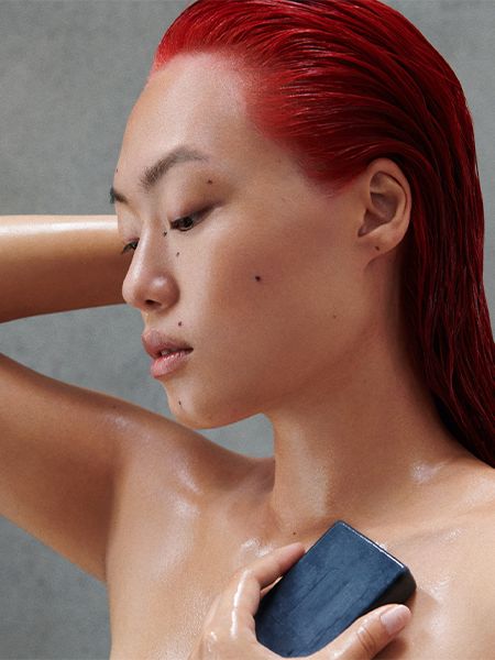 Woman with wet red hair uses Shampoon Bar in the shower