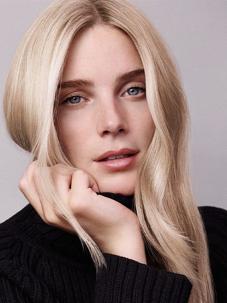 Woman with light blonde hair wears black turtleneck sweater and looks cozy