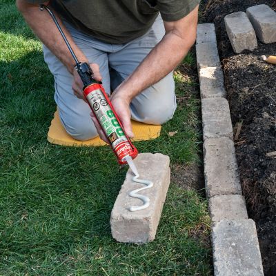 man using lepage pl 600 landscape block adhesive on concrete block