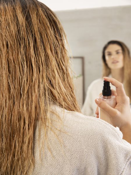 Woman looking in the mirror and using the Gliss Split Hair Miracle Sealing Serum
