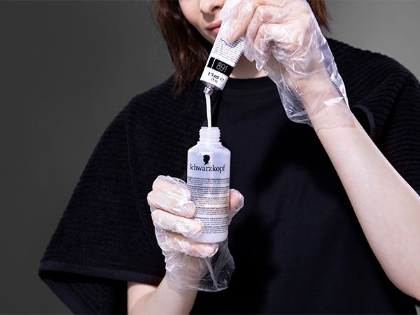 Žena istišće kremu za bojenje iz tube u bočicu za razvijanje