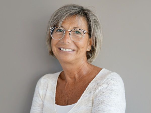 Femme aux cheveux gris avec un carré tendance, des lunettes et un haut blanc