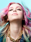 Woman with multicolored hair and chunky gold necklace tilting her head back
