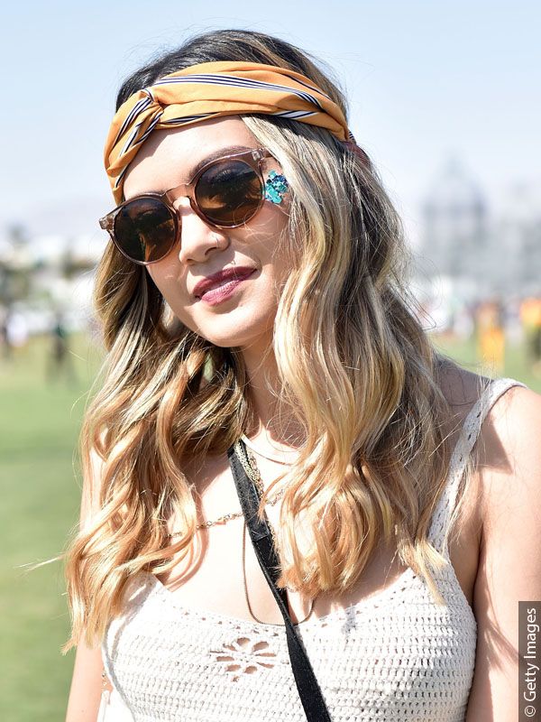 Festival-Besucherin mit blonden Wellen im Boho-Look, Sonnenbrille und einem bunten Seidentuch im Haar