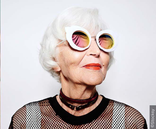 Older woman with white hair and stylish glasses.