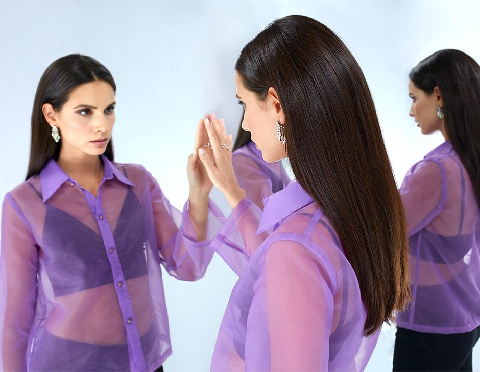 Темноволосая женщина смотрит на себя в зеркало