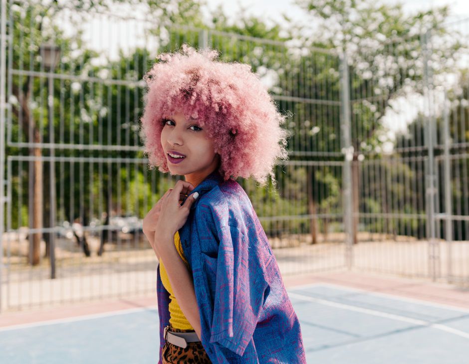 Femme aux cheveux rose bouclés avec un kimono sur un terrain de basket