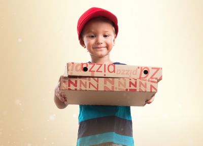 Un garçon avec une casquette rouge transporte une boîte de pizza en carton ondulé