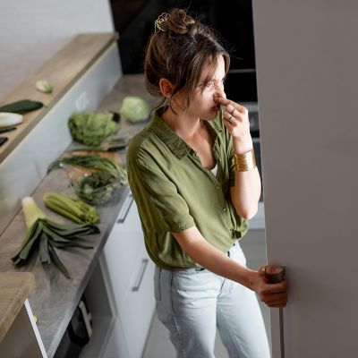 woman covering her nose from bad odors in her kitchen