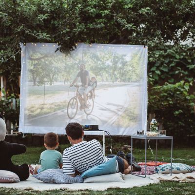 Mężczyzna i chłopiec oglądają film na projektorze w ogrodzie