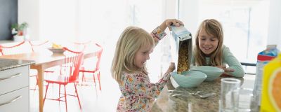 sisters pouring cereal in the kitchen