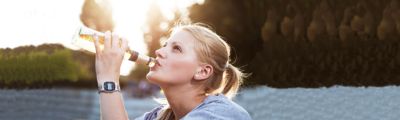 Donna che beve da una bottiglia di vetro