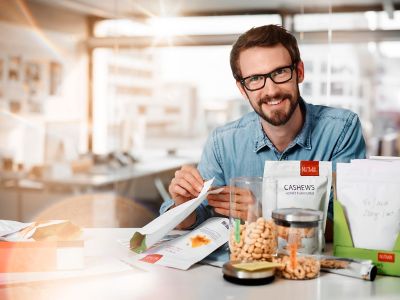 packaging product designer sitting at his working place with a nuts stand-up pouch in his hands