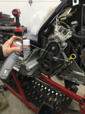 spraying Loctite SF 7635 pro strength degreaser insider a snowmobile chain case