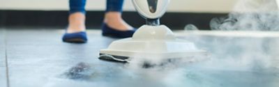 woman steam cleaning tiles
