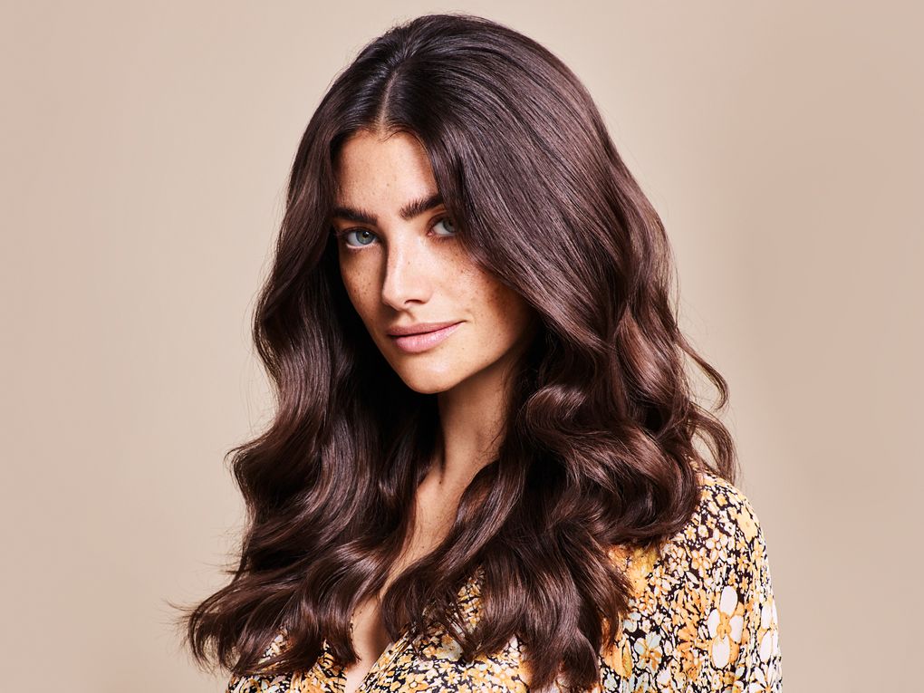 Jeune femme aux longs cheveux ondulés avec une coloration châtain doré 