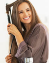 Brunette woman in dressing gown using a flat iron