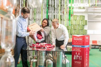 three people examining loctite bottles ready for recycling