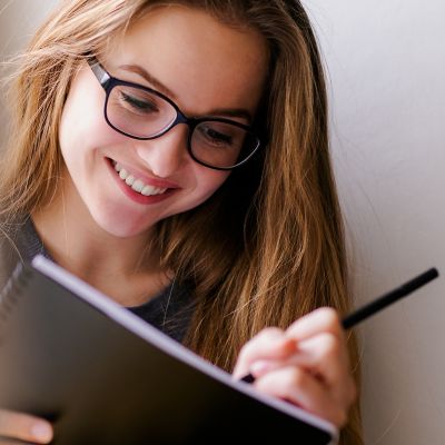 Uśmiechnięta kobieta pisze w notatniku