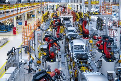 Multiple silver car bodies on an assembly line in a factory setting