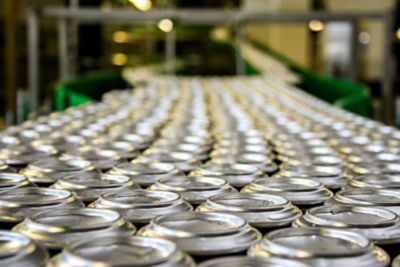 Thousands of aluminum beverage cans on a conveyor belt line in a factory