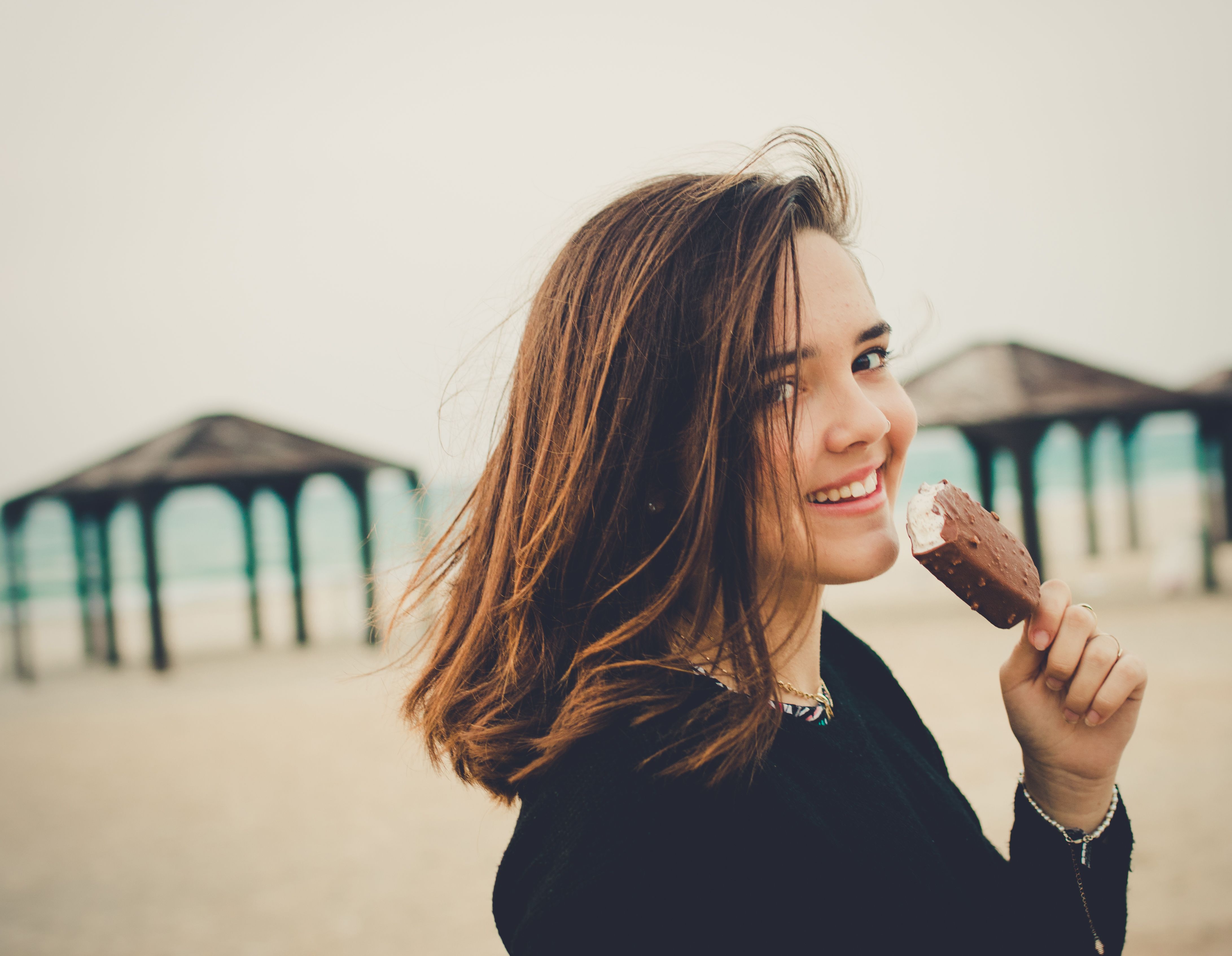 Jeune fille brune en train de manger une glace à la plage