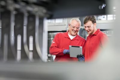 Two men in safety glasses having a conversation and looking at tablet