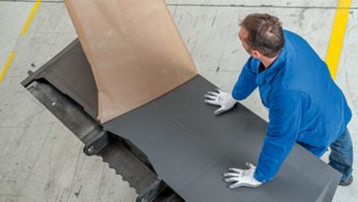 Cropped photo of two men removing adhesive film covering from an aircraft spoiler during a structural adhesive film application manufacturing process