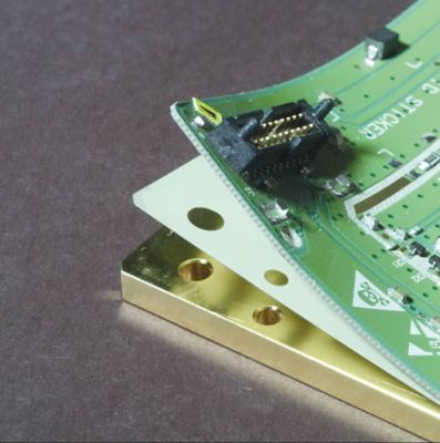 Photo of custom cut film adhesive substrate between layers of an electronic assembly green pcb is lifted to expose the layer of film