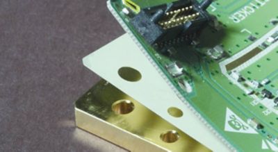 Cropped photo of custom cut film adhesive substrate between layers of an electronic assembly green pcb is lifted to expose the layer of film