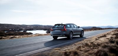 Grey Volvo sport utility vehicle driving down an empty desert road