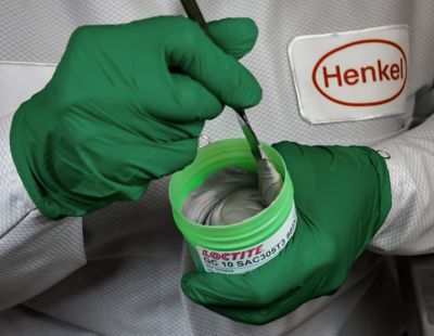 Photo of henkel engineer wearing green gloves stirring a green jar of loctite gc 10 solder paste