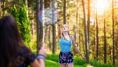 Two women playing badminton in the woods