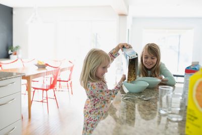 sisters pouring cereal in the kitchen