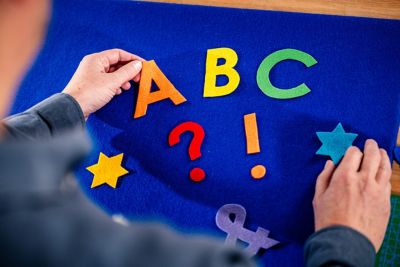 A blue felt board with felt letters and stars.