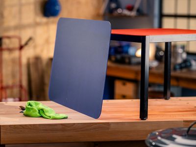A plastic tabletop is leaning against a metal table frame.