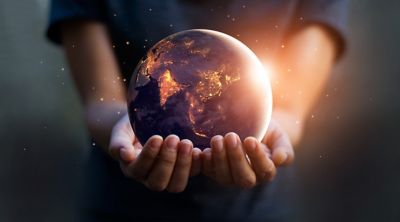 Illustration of person in black shirt holding in the palms of their hands a 3D image of earth from space at night with lights on shutterstock ID 1063994879