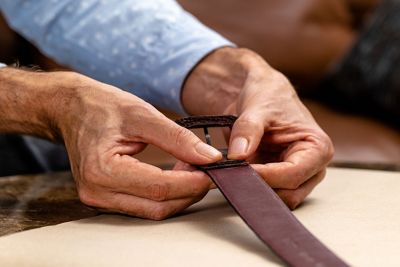 Hands pressing glued leather belt