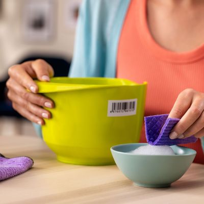 A plastic bowl with a price label next to a hand dipping a cloth in soapy water