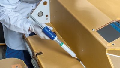 Cropped photo of man applying a bead of structural adhesive paste or sealant to a metal or composite joint during a manufacturing process