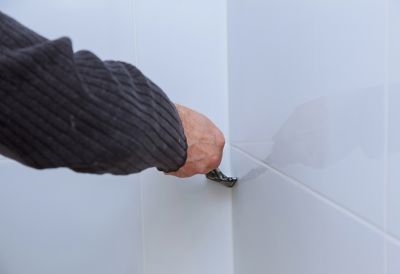 Handwerker entfernt Silikonreste von einer Badewanne