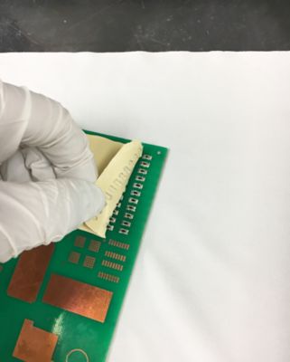 Photo of gloved hand peeling back bergquist peelable thermal interface material from printed circuit board this unique liquid gap filler material offers post-assembly reworkability