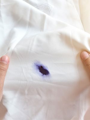 Weißes Kleidungsstück mit dunkelblauem Kugelschreiberfleck