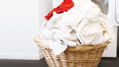 Beyaz çamaşır ve kırmızı bir giysi ile dolu hasır sepet.